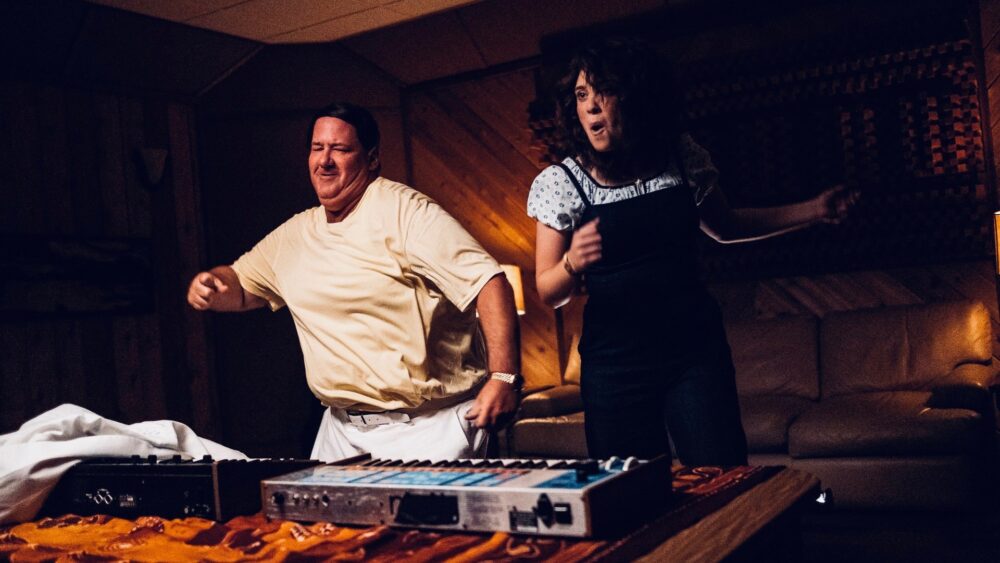 Energetic duo dancing by keyboards, possibly promoting "Electric Jesus.