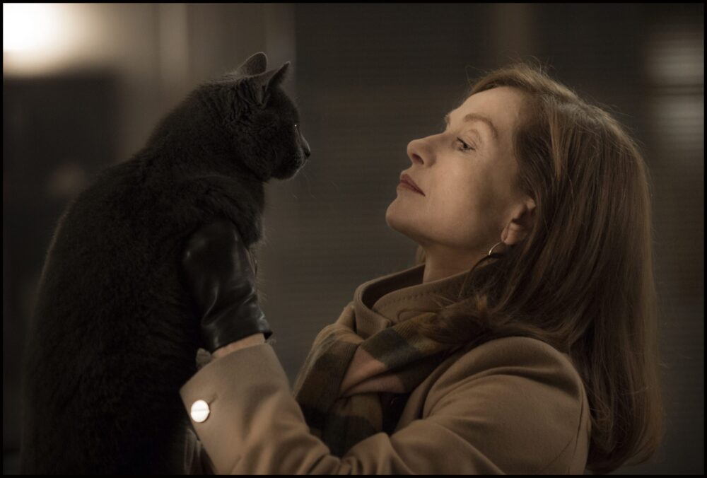 Isabelle Huppert in "Elle" holds a gray cat wearing a leather glove.