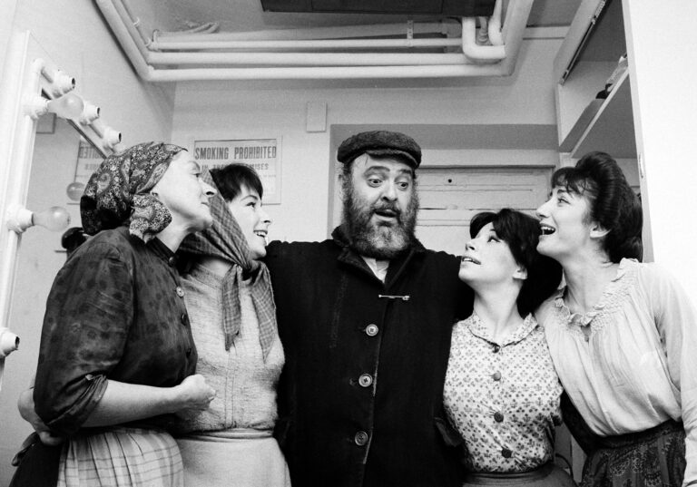 Cast of Fiddler on the Roof backstage, smiling and embracing.