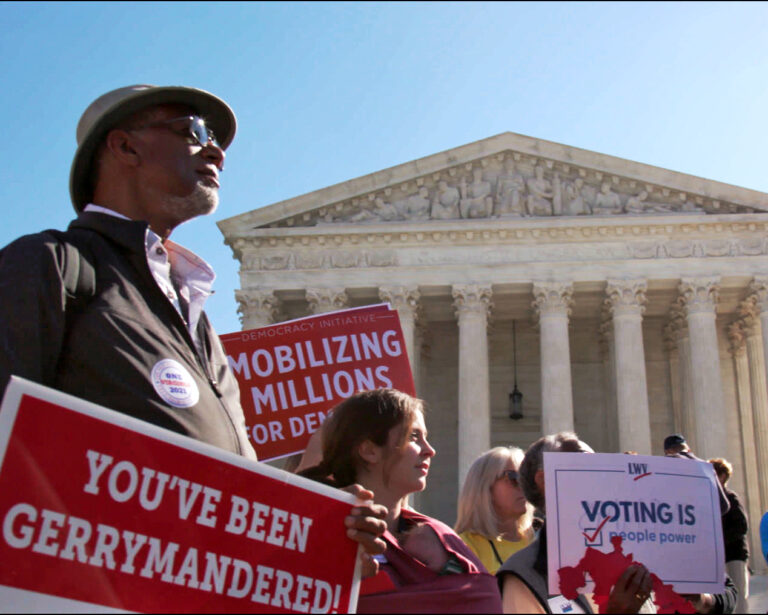 People protesting gerrymandering in front of the Supreme Court, holding signs.