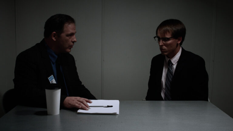 Interrogation scene: Detective questions a man in a suit across a table.