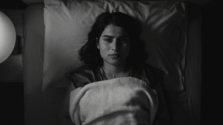 Black and white image of a woman lying in bed, wrapped in a blanket.