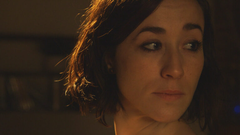 Close-up of a woman with short brown hair looking thoughtfully to the side.