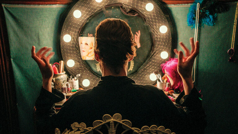 Performer in dressing room with lighted mirror, getting ready for a freak show.