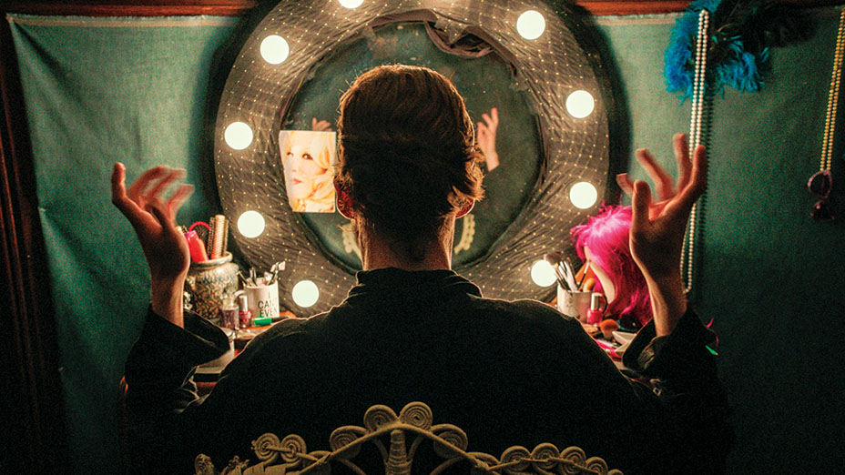 Performer in dressing room with lighted mirror, getting ready for a freak show.