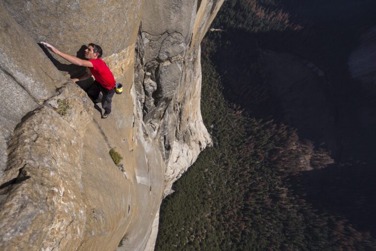 Free solo climber Alex Honnold wearing a red shirt climbing El Capitan, Yosemite.