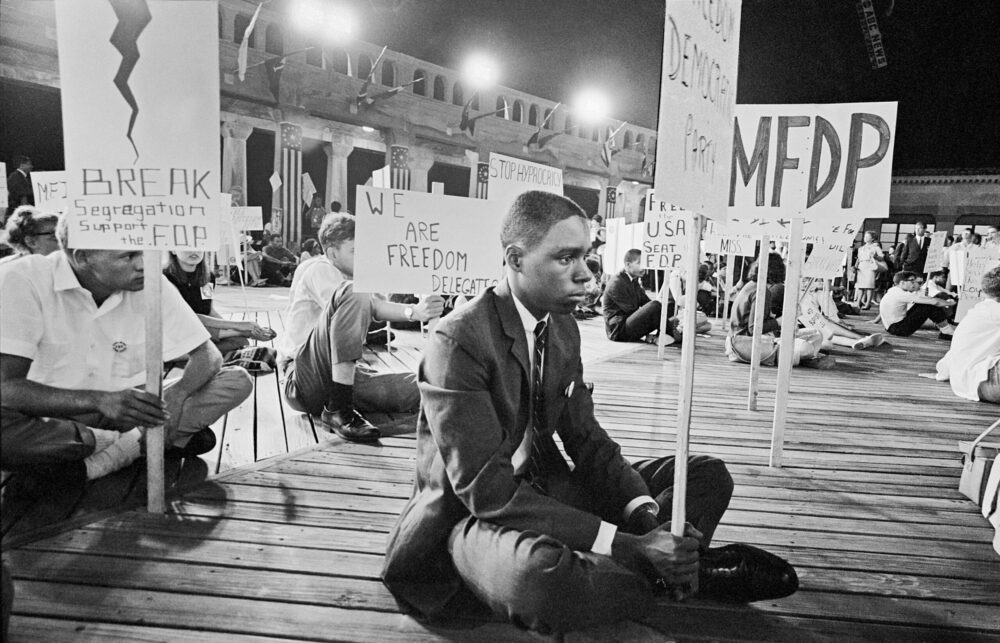 Civil rights activists protest segregation during Freedom Summer. MFDP sign visible.
