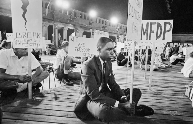 Civil rights activists protest segregation during Freedom Summer. MFDP sign visible.