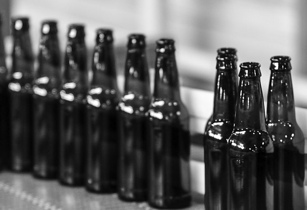 Row of brown glass beer bottles, ready for filling.