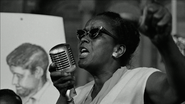 Ella Baker speaking at a podium with a microphone. Civil rights activist.