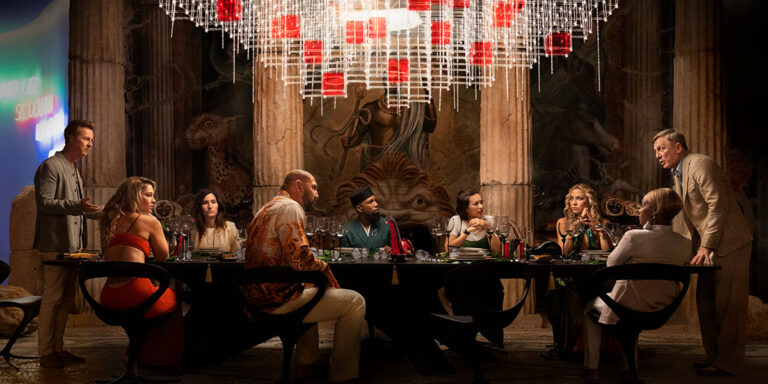 Cast of Glass Onion: A Knives Out Mystery at a dinner table.