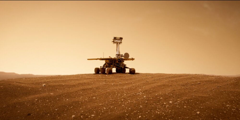 Mars rover on a dusty, reddish landscape.