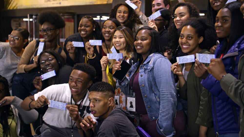 Group of diverse students holding tickets, excited about "Giving Voice.