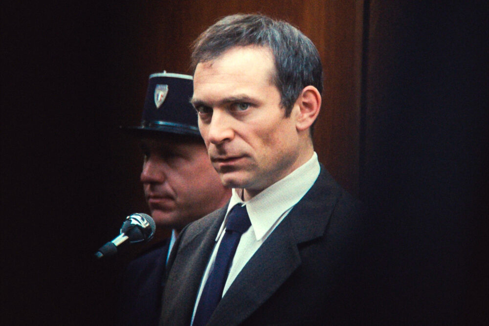 Man in court, possibly related to "The Goldman Case", wearing a suit and tie.