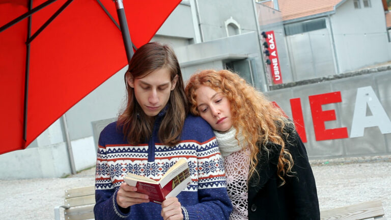 Couple reading under red umbrella; "Usine a Gaz" sign visible.
