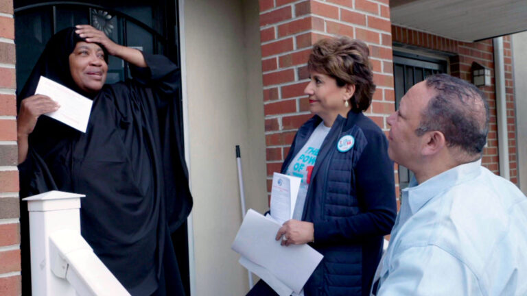 People discussing politics at a door, possibly part of a Gumbo Coalition campaign.