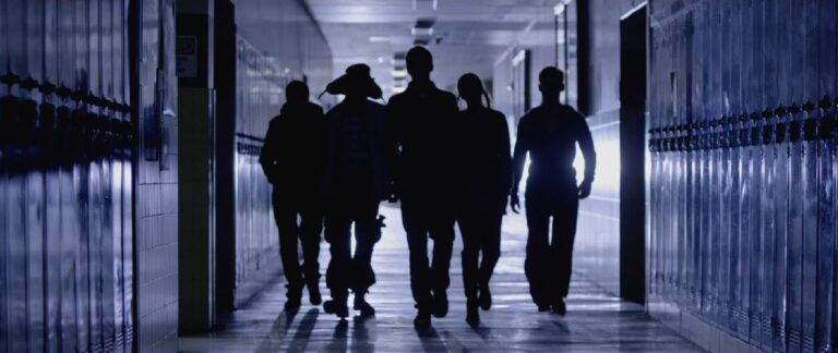 Silhouetted group walking down a school hallway with lockers.
