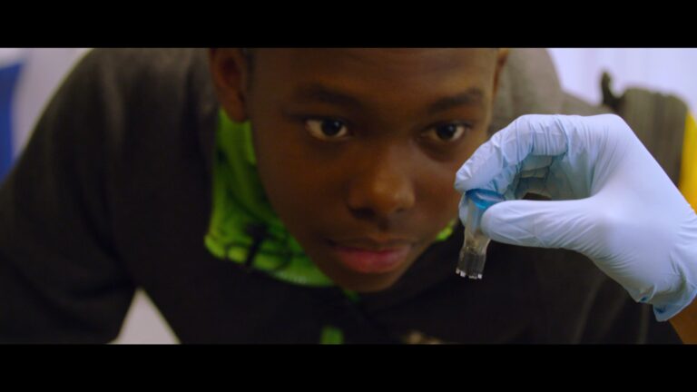 Teen looks at a gloved hand holding a vial. Science and human nature concept.