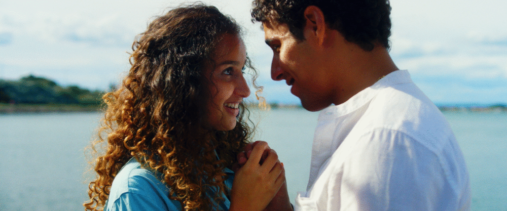 Young couple gazing at each other lovingly by the water.