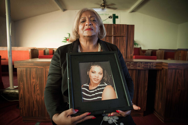 Grieving mother holding photo of daughter, memorializing a life lost.