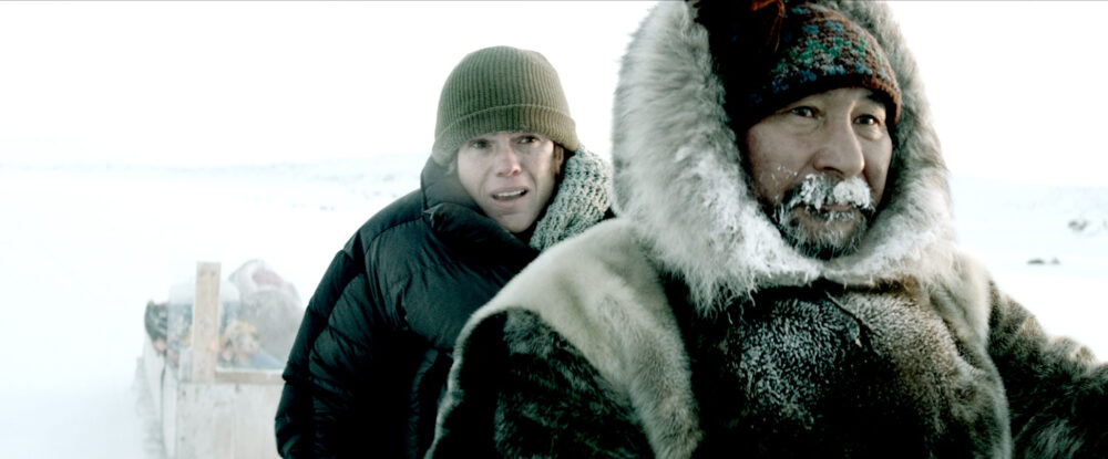 Two people in Arctic clothing in a snowy landscape.