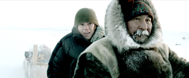 Two people in Arctic clothing in a snowy landscape.