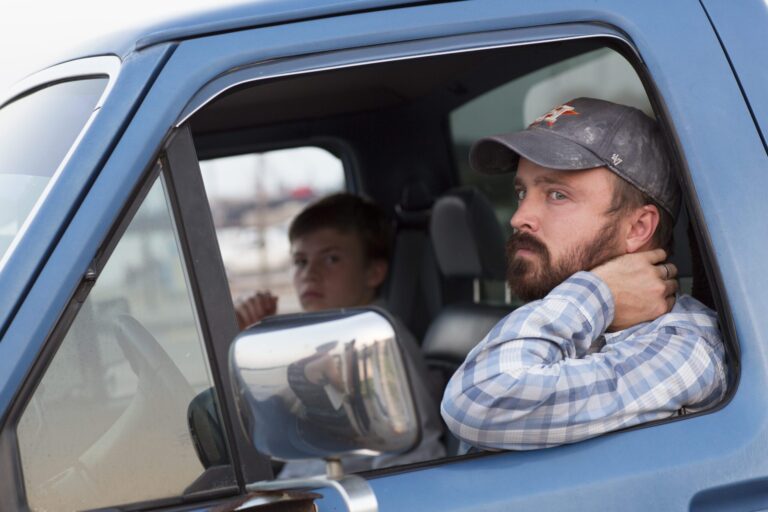 Aaron Paul in "Hellion" driving a blue truck with a young boy.