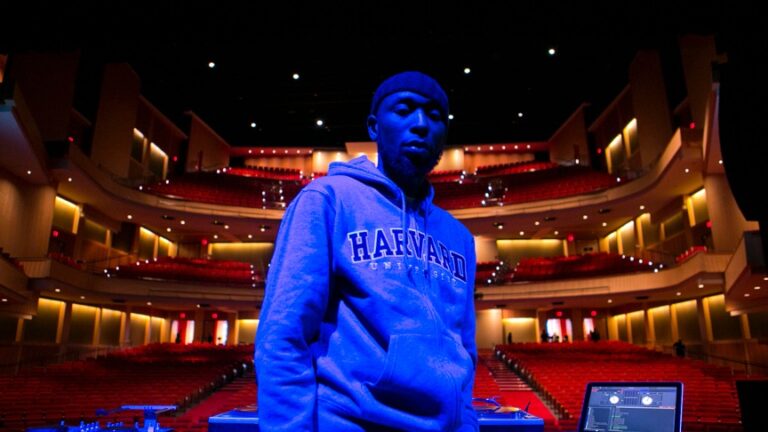 DJ wearing a Harvard hoodie in an empty theater.