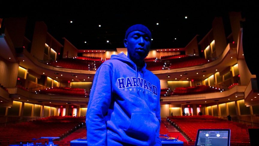 DJ wearing a Harvard hoodie in an empty theater.
