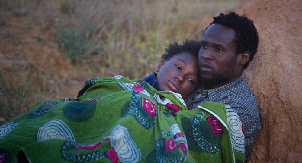 Man comforts a child wrapped in a blanket. A scene of hope and care.