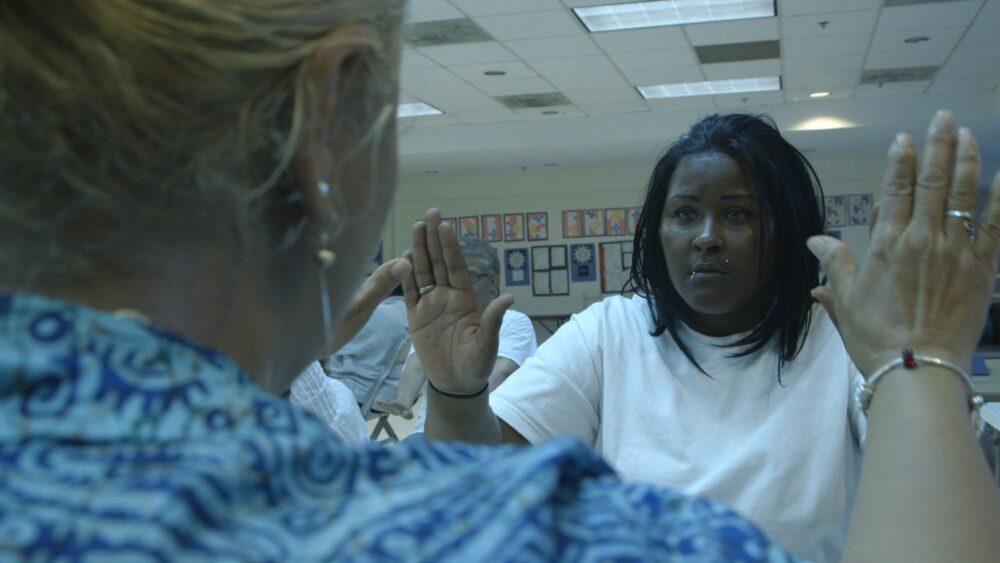 Woman with hands raised, possibly in a group therapy session.