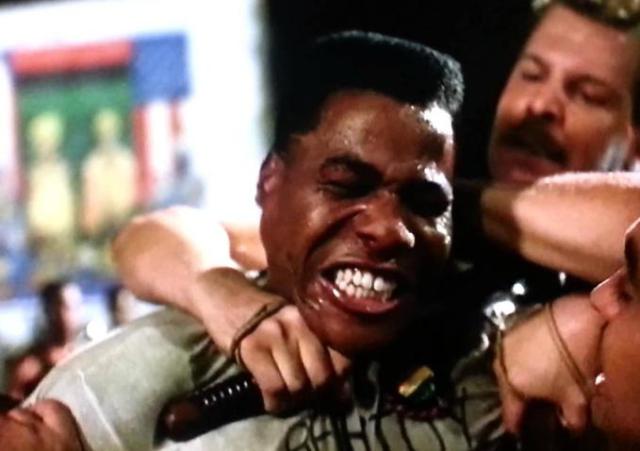Man being choked, distressed expression.
