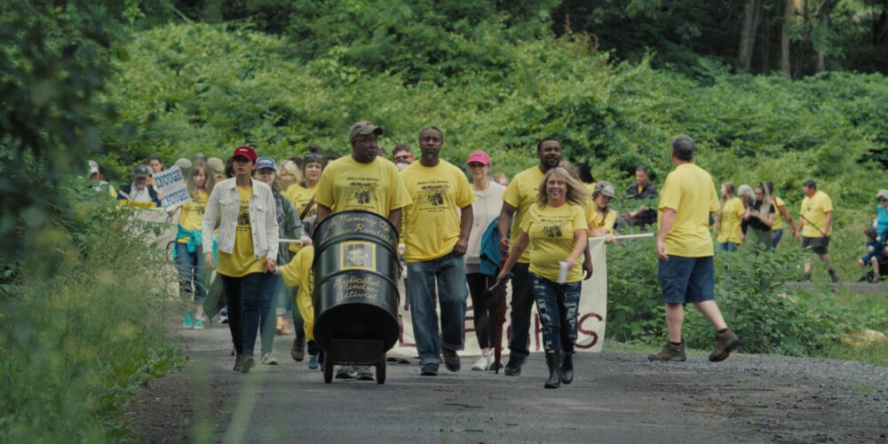 People marching for Minden, holding a barrel with "In Memory Of Lucian Randale" text.