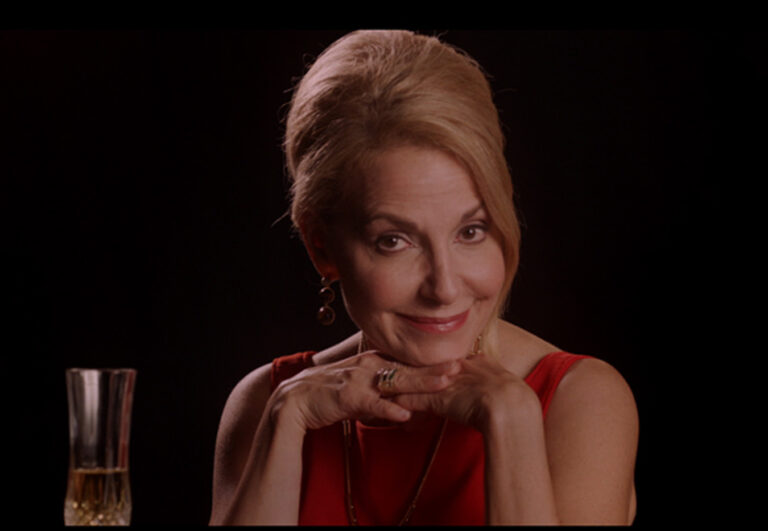 Confident woman in red dress with a beehive hairstyle, smiling.