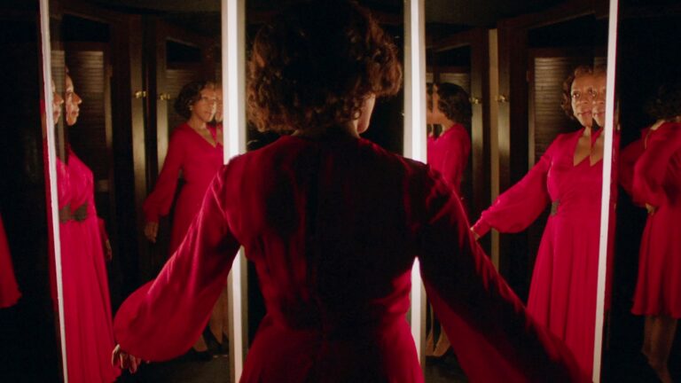 Woman in red dress surrounded by mirrors, reflecting the style of "In Fabric