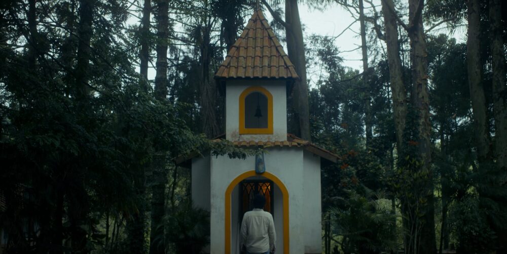 Small chapel in a forest, person standing at the entrance.
