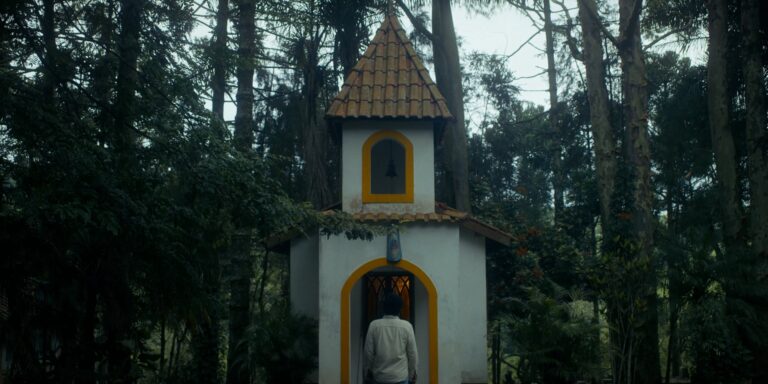 Small chapel in a forest, person standing at the entrance.