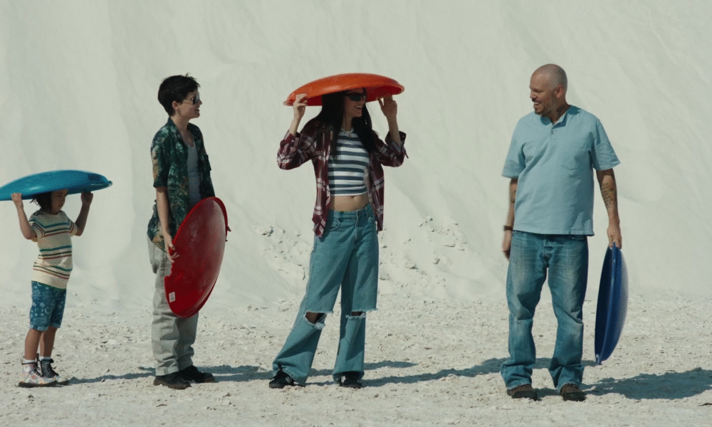 Family with colorful sleds on white sand dunes, "In the Summers
