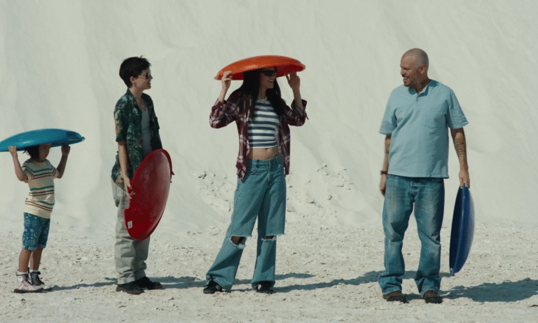 Family with colorful sleds on white sand dunes, "In the Summers