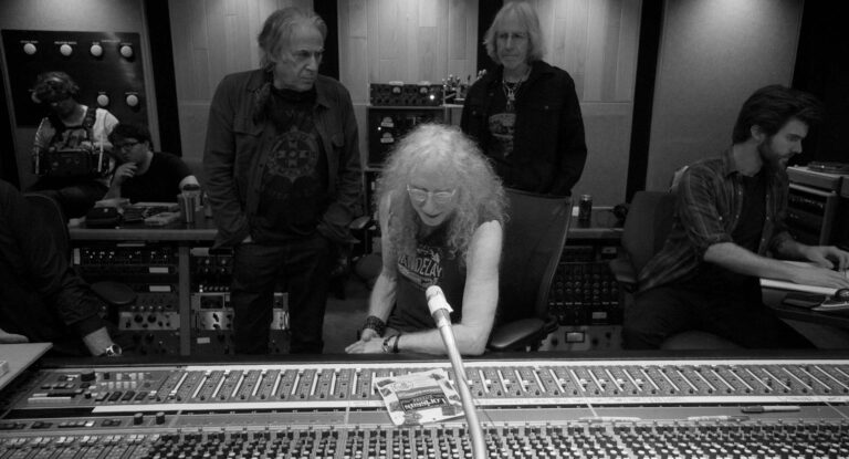 Immediate Family band members in a recording studio with mixing console.