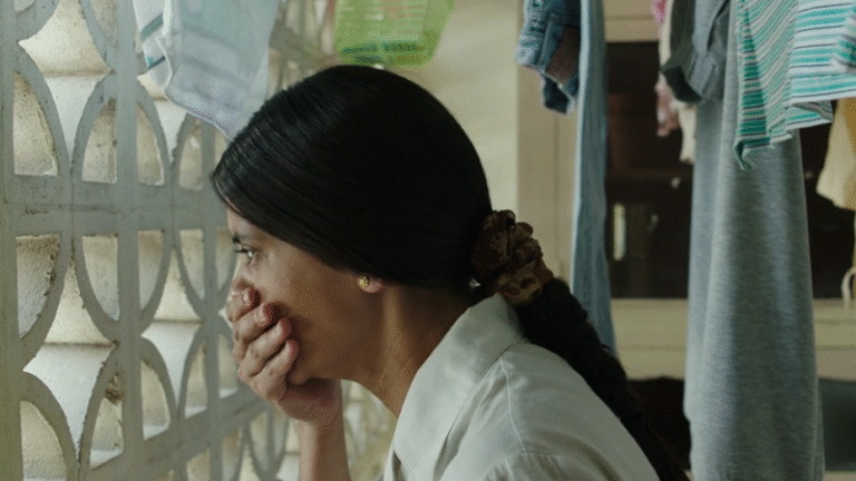 Woman looking through a window, hand covering her mouth.