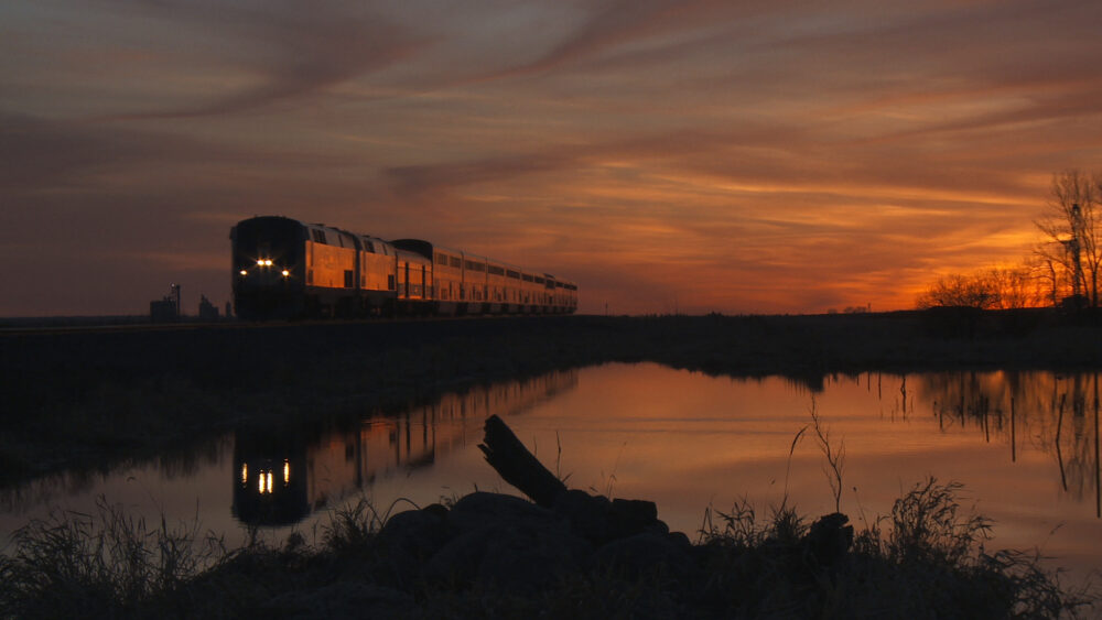 Train at sunset reflected in still water.