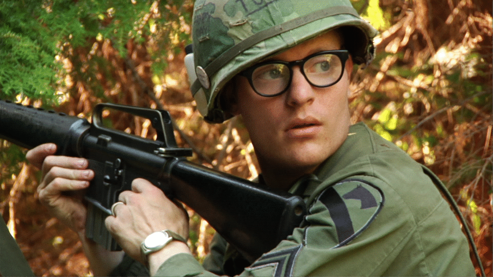 Soldier in Vietnam War era uniform with M16 rifle.