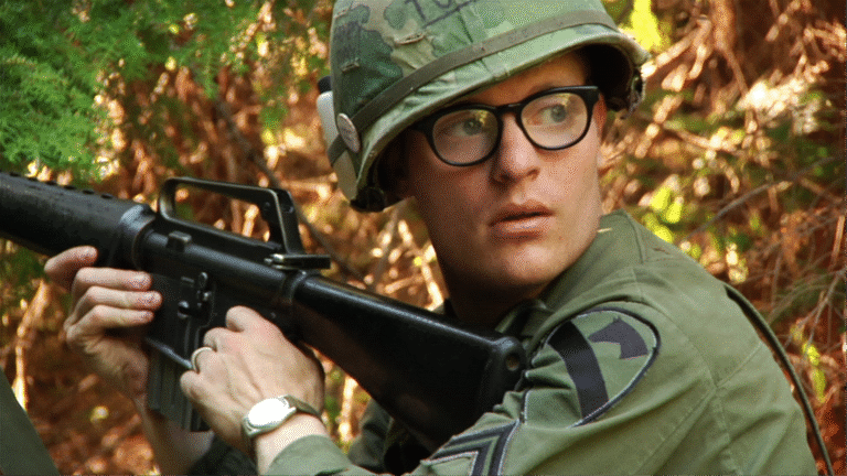 Soldier in Vietnam War era uniform with M16 rifle.