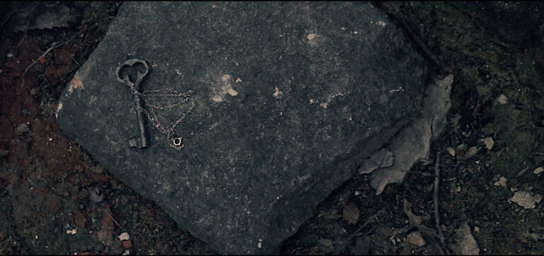 Antique key and necklace on a stone, possibly related to "Incubus.