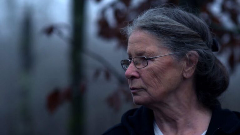 Portrait of Ingrid, an older woman with gray hair, outdoors in a foggy setting.