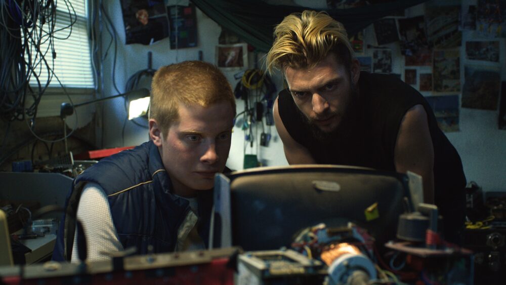 Two men intensely focused on a computer screen in a cluttered room for "Jackrabbit"