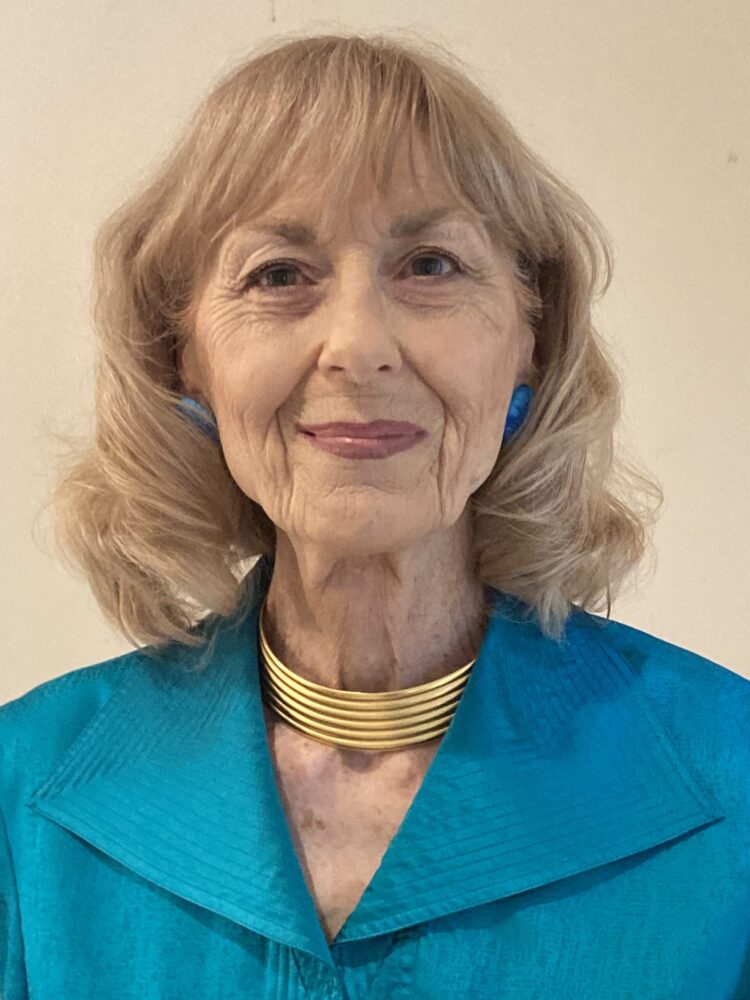 Jacquelyn Pogue portrait. Woman with blonde hair, wearing blue jacket and gold necklace.