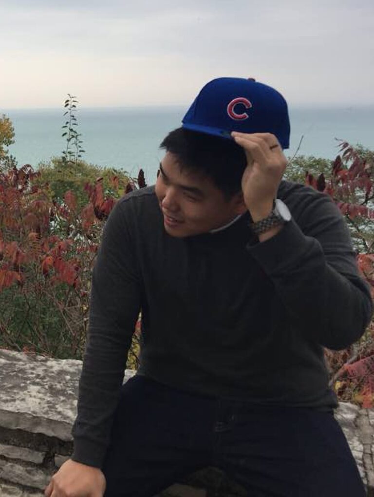 Jason Park wearing a Cubs hat, sitting outdoors with a lake view.