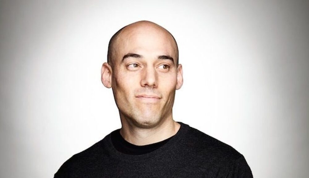 Portrait of Joshua Oppenheimer, bald and looking to the side with a slight smile.